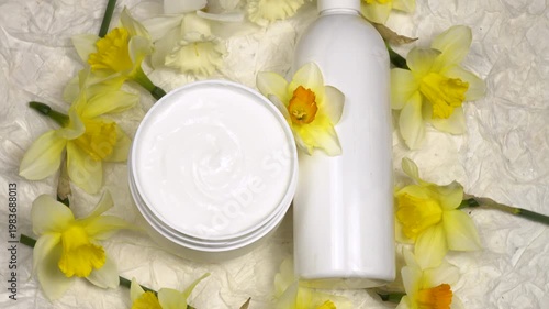 Jar and bottle with body cream, fresh flowers daffodil are on a white background, cosmetics based on daffodils