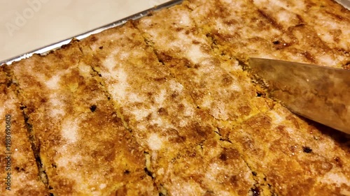 Freshly baked shortbread pie is cut into portions with a knife