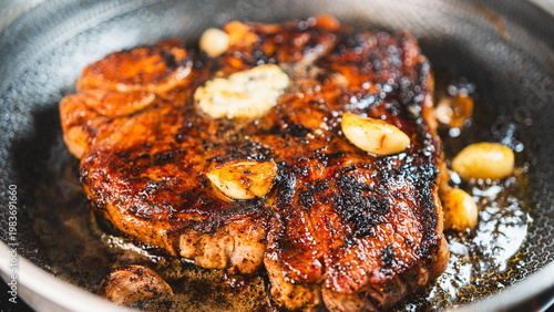 Φωτογραφία Juicy T-bone steak searing in a cast iron pan with garlic and fresh herbs, captured from above in a dark rustic kitchen setting