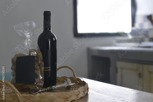Bottiglia di vino nero con una busta di taralli in una cucina di un'antica masseria