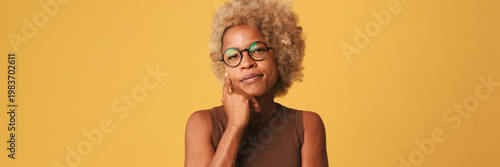 Bild auf Leinwand Beautiful girl in glasses, wearing brown top listens attentively to someone and disagrees isolated on orange background