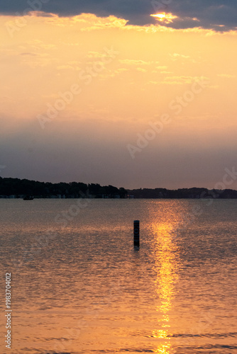 Peaceful summer sunrise reflecting on a calm lake with a single buoy in Waukesha County, Wisconsin. Early morning light in July.