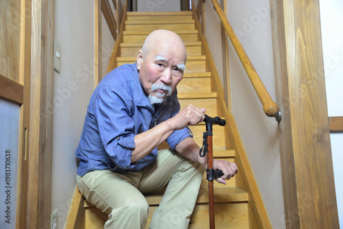 室内の階段で杖を使用してリハビリをしているヒゲの老人