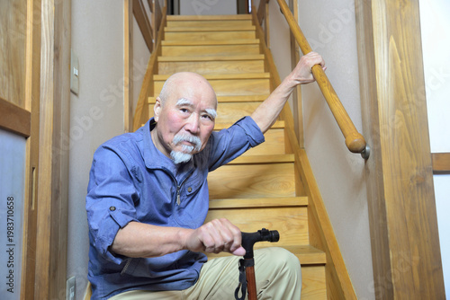 室内の階段で杖を使用してリハビリをしているヒゲの老人