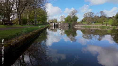 Tranquil canal lock with tree-lined banks and cloud reflections