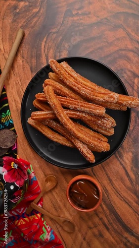 Typical churro dessert with artisanal chocolate and Mexican decorative elements. Camera rotating from an aerial view