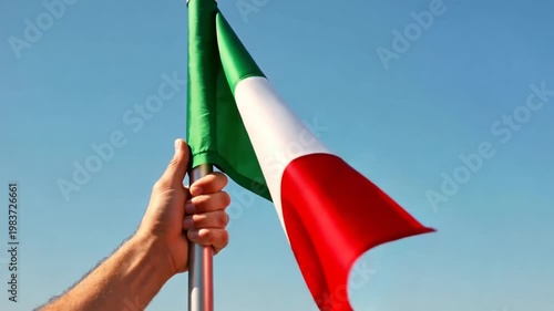Person holding Italian flag against blue sky