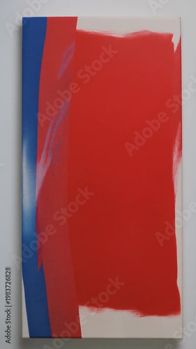 Abstract painting with red and blue brushstrokes on white canvas indoors