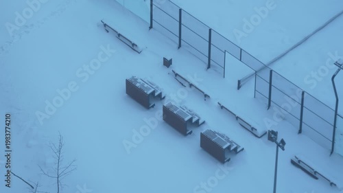 tennis court and park seating covered in snow aerial view winter urban environment