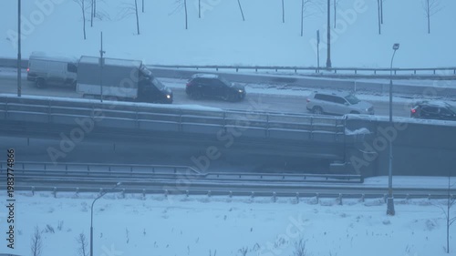 Winter highway traffic in snowfall, cars driving on snowy road, cold weather transport, urban commute in snowstorm