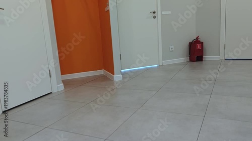 Interior view of modern hallway with orange accent wall, three doors, and a fire extinguisher positioned against the wall, showcasing a clean and organized space