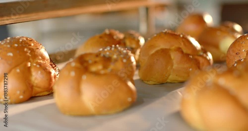 Vertical video: Focusing camera drawing braided rolls into sharp view on bakery rack, showing seeds