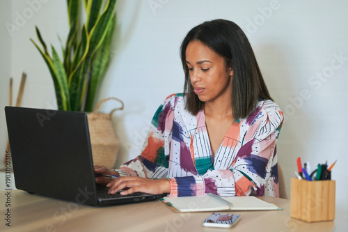 Focused woman working from home typing on laptop concentrating on her online business