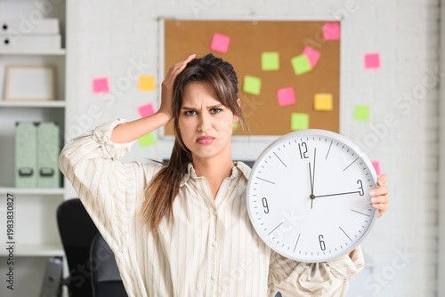 Young businesswoman with clock in office. Deadline concept