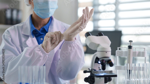 Photos Asian adult scientist preparing laboratory work putting on sterile gloves medica