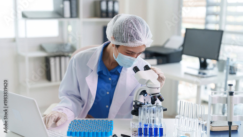 Asian adult scientist researcher medical professional conducting experiment analyzing samples using microscope focused professional dedicated scientific discovery 