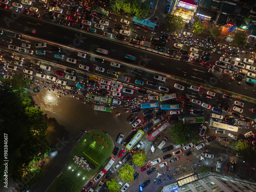 Dense traffic congestion at a flooded intersection in Hanoi during nighttime, with cars and buses trapped in rising water after heavy rain.
