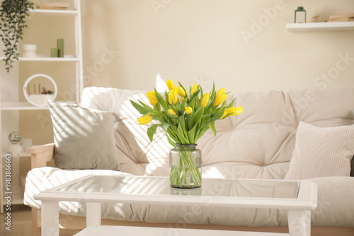 Comfortable white sofa with vase of tulips in light living room
