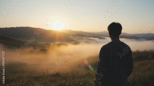 silhouette of a man watching sunrise over foggy valley