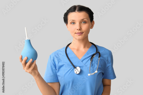 Female doctor with enema on light background