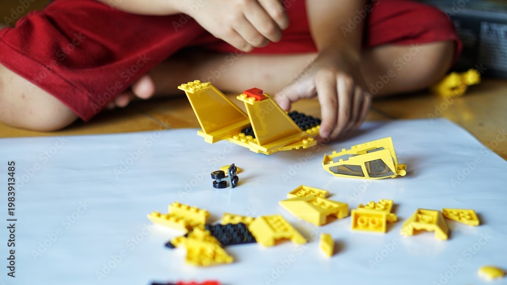 Fototapeta premium Close up of child's hands playing with colorful plastic bricks or lego. Toddler having fun and building out of bright constructor bricks. Development toys