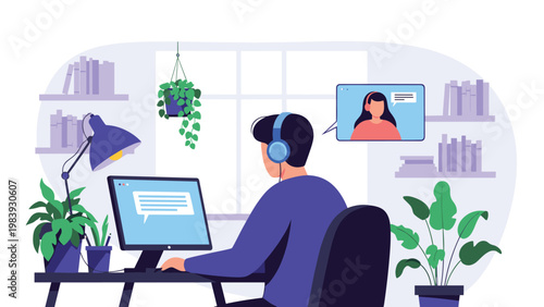 Young man wearing blue headphones while participating in a video call on a desktop computer in a cozy room with bookshelves.