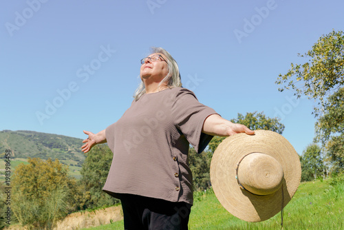 Принти на полотні Senior woman standing outdoors on a green hill, feeling liberated and peaceful w