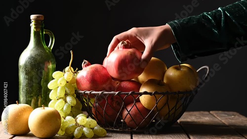Hand Reaching for Ripe Pomegranate From Basket Full of Fresh Fruits, Still Life Composition