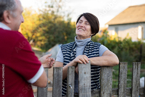 Positive mature man and woman standing near fence in garden