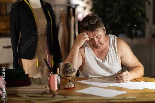 Photography Middle-aged tailor struggling with paperwork in fashion studio
