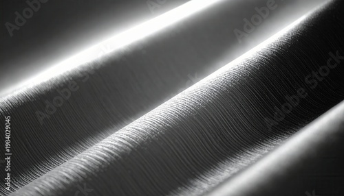 빛과 그림자가 교차하며 만들어내는 깊이감 있는 물결무늬와 섬세한 질감이 돋보이는 추상적인 회색 표면 배경으로, 현대적이고 우아한 디자인 콘셉트에 적합합니다.