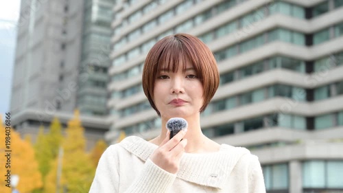 ビル前でピンマイクを使って話す日本人女性