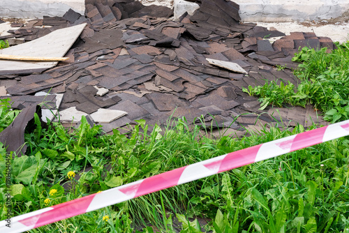 The discarded roof shingles and debris have been marked with caution tape.