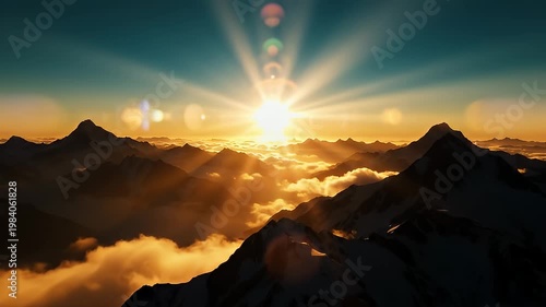 Dramatic sunburst over majestic mountains above clouds at sunrise