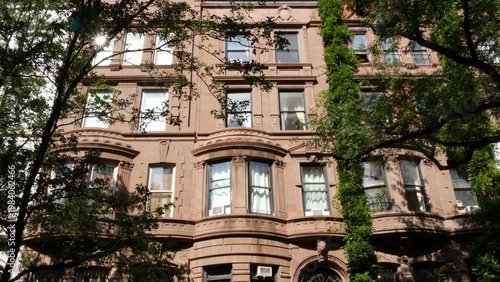 New York City townhouse buildings, brownstone row houses in Manhattan or Brooklyn, United States of America. Classic buildings on residential district street. Real estate property. Rowhouse townhome.