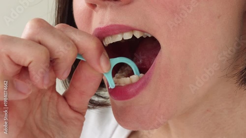 Young Woman Using Blue Plastic Dental Floss Pick on White Healthy Teeth — Female Interdental Cleaning with Disposable Flosser, Oral Hygiene Daily Routine, Gum Care and Preventive Dentistry