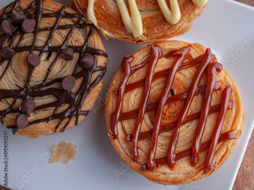 Reposteria casera, pan de hojaldre sobre un plato blanco para disfrutar en familia con cafe o leche, cubierta de cajeta vista cenital.