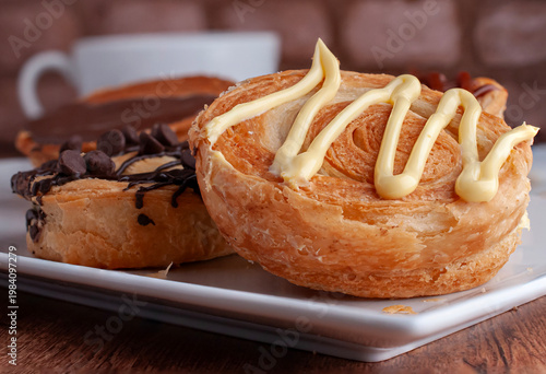 Reposteria casera, pan de hojaldre sobre un plato blanco para disfrutar en familia con cafe o leche, vainilla o crema pastelera