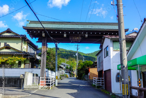 Traditional temple gate along Shikoku Henro street with rural village houses and blue sky in Japan