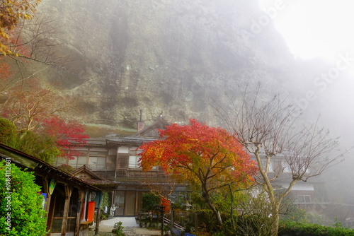 Misty mountain temple on Shikoku Henro with autumn maple tree and traditional buildings in Japan