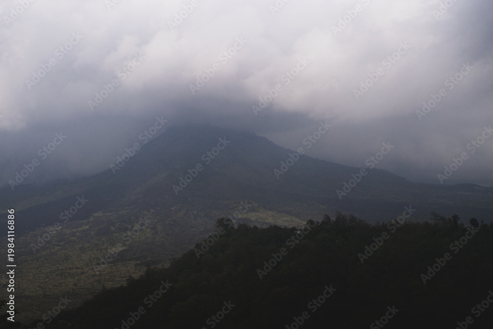 Fototapeta premium Moody tropical volcano peak shrouded in storm clouds in Bali