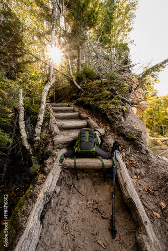 Hiker's backpack and trekking poles resting on forest trail steps