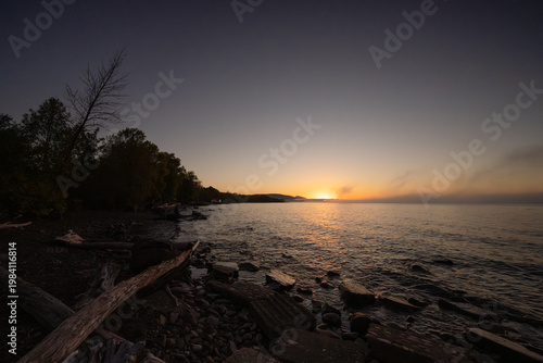 Sunset reflecting on lake water with shore and trees