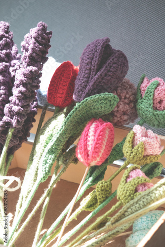 Leisure time, hobby activity. Wool knitting flowers. Colorful knitted flowers. Handmade idea concept. Copy space, blank, empty. No people, nobody. Vertical photo.