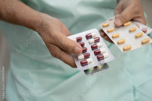 Asian elderly woman holding pill drug in hand, strong healthy medical concept.