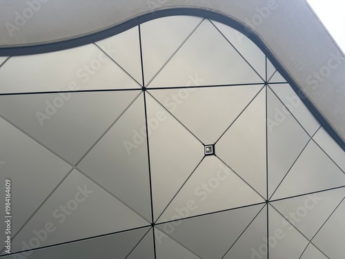 Curved geometric ceiling under modern awning with minimalist triangular panel design
