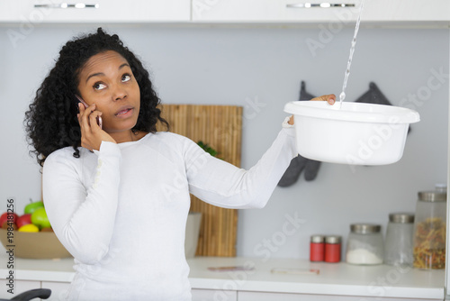 Obraz na płótnie woman calling plumber to fix water leaking from ceiling