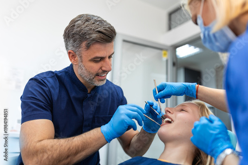 Fotografie Professional dentist and assistant treating young woman