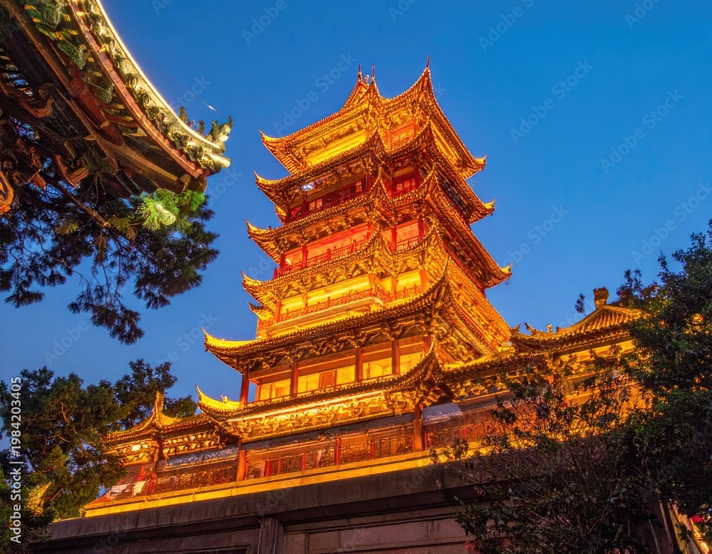 Fototapeta premium A stunning nighttime view showcases the intricate architecture of the ancient Chinese temple, illuminated by warm golden lights against a vibrant blue sky.