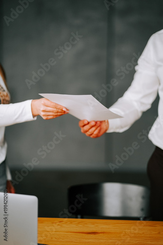 Business meeting involves document exchange between two professionals in an office setting